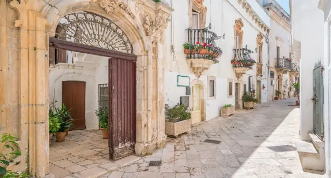 Whitewashed street in Martina Franca, Apulia, with floral balconies.