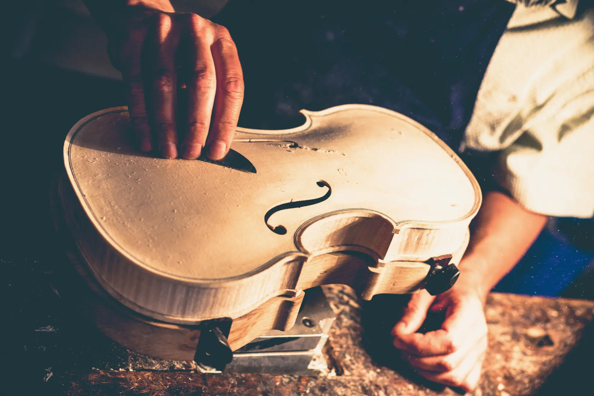 A craftsman’s hands shaping a violin with precision and care.