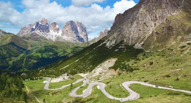 Towering peaks of the Dolomites with a scenic mountain road, an ideal setting for a milestone holiday in Italy.