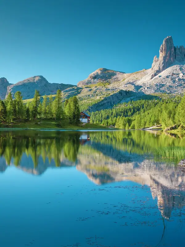 Towering Dolomite peaks mirrored in a crystal-clear mountain lake during summer.