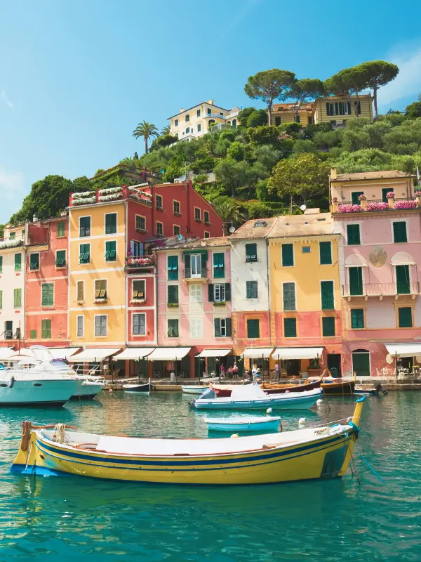 A moored boat in Portofino harbour with colourful houses in the background during springtime.