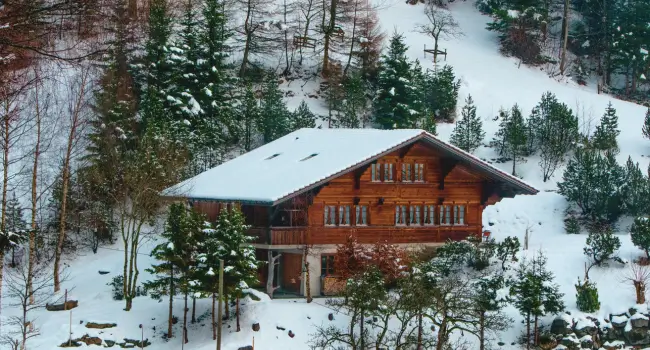 Romantic wooden mountain chalet surrounded by snow-covered trees, ideal for an anniversary getaway.