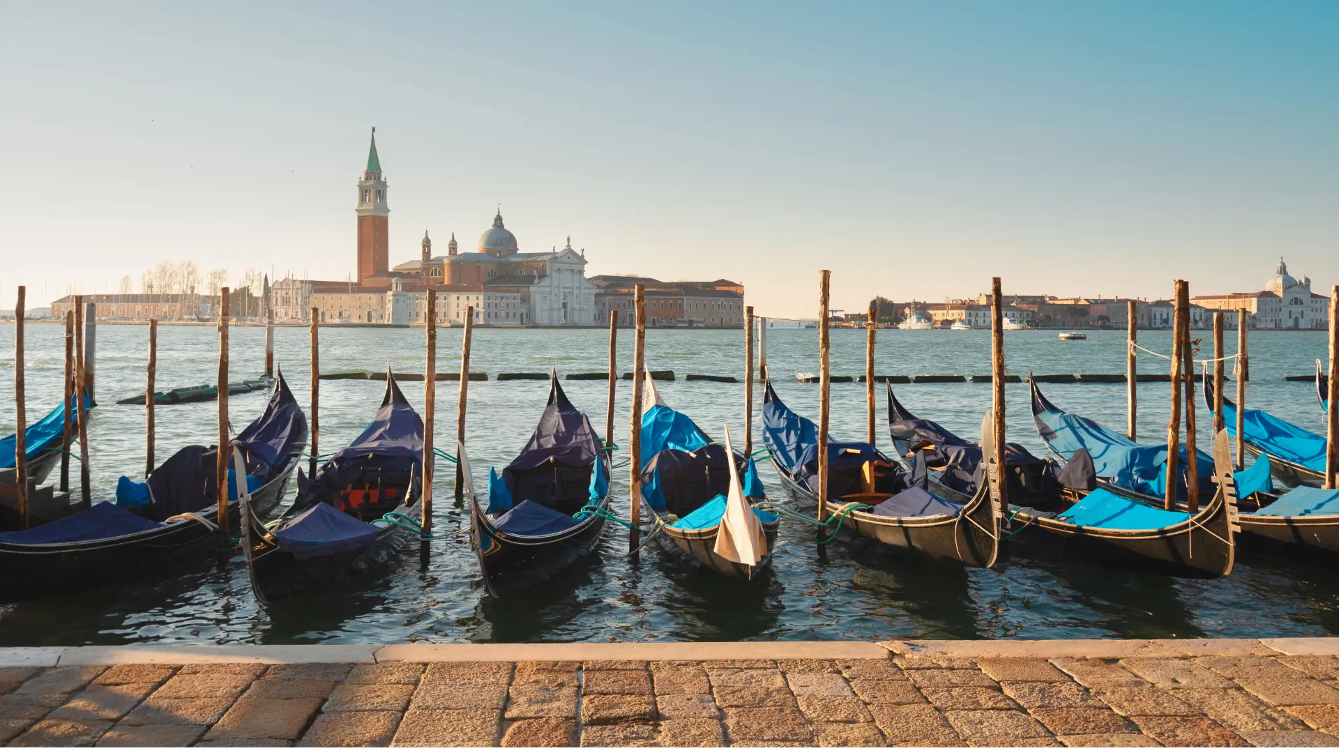 Venice canal at sunrise — autumn holidays in Italy, gondolas moored, San Giorgio Maggiore in the distance