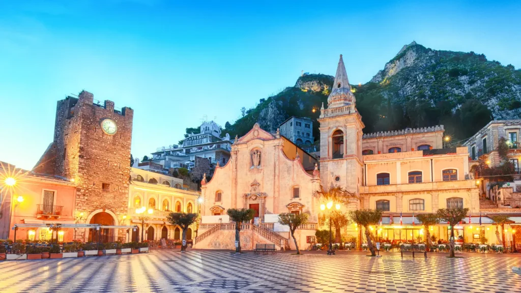 Piazza IX Aprile in Taormina at dusk, with the clock tower and church