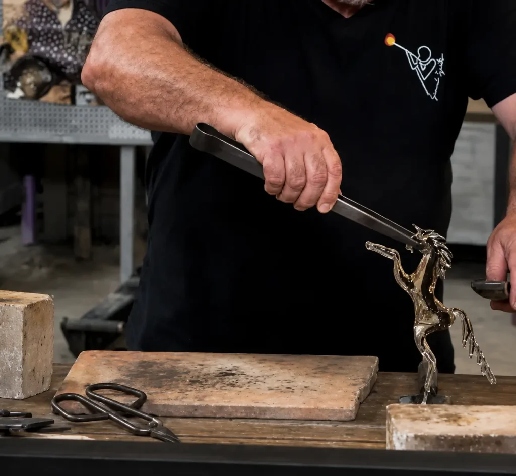 A Murano glassmaker holding a finished glass horse