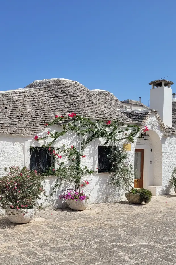 A whitewashed trullo with a flowered doorway in Alberobello, Puglia