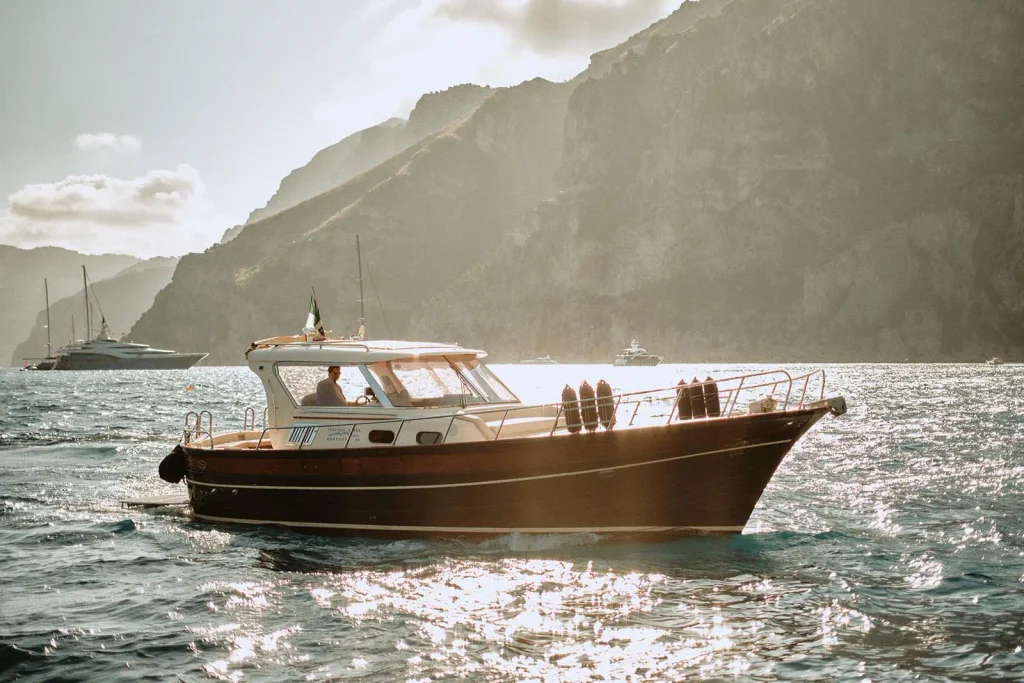 Private boat on the secret Amalfi Coast, traditional gozzo with skipper below the cliffs