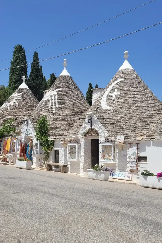 White symbols painted on the conical roofs of three trulli in Alberobello, Puglia, a UNESCO World Heritage site