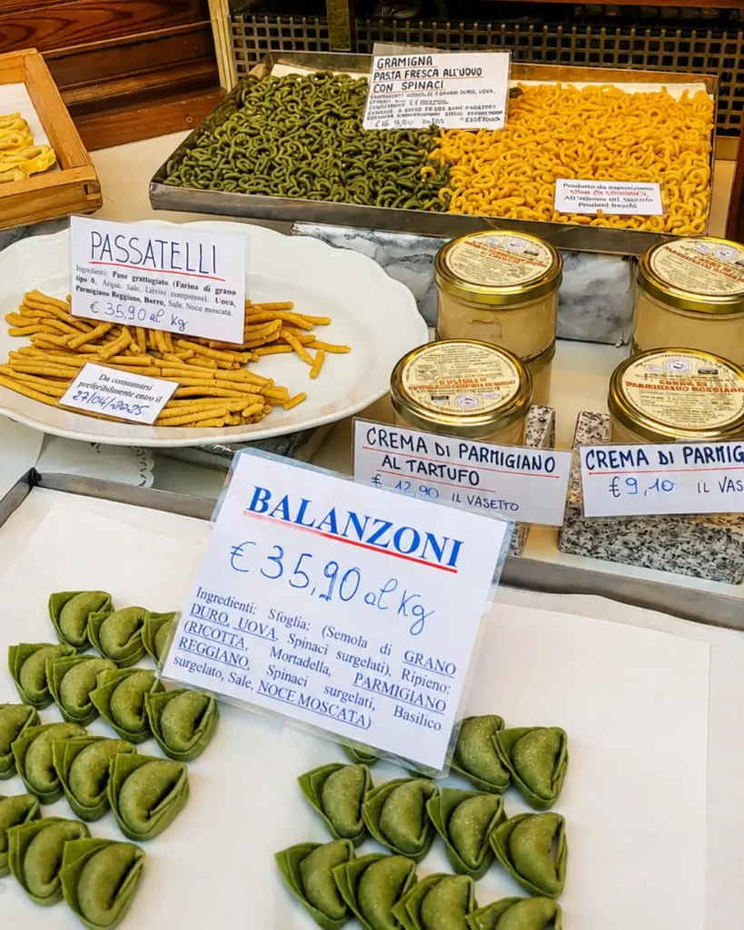 Fresh tortellini, passatelli and balanzoni on display in a Bologna pasta shop, with prices marked on cards